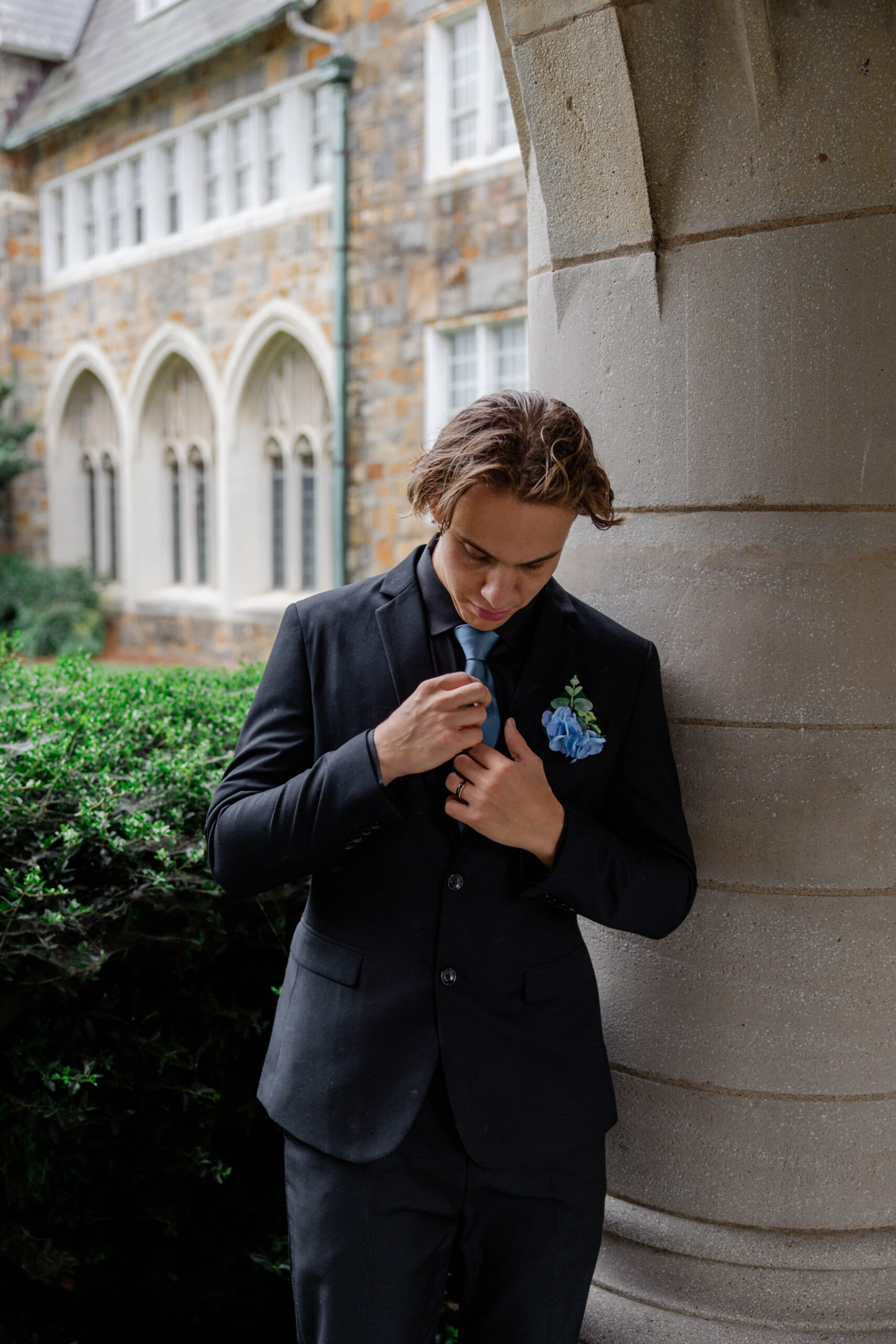 groom adjusts his tie as he prepares for his wedding day in the rain!