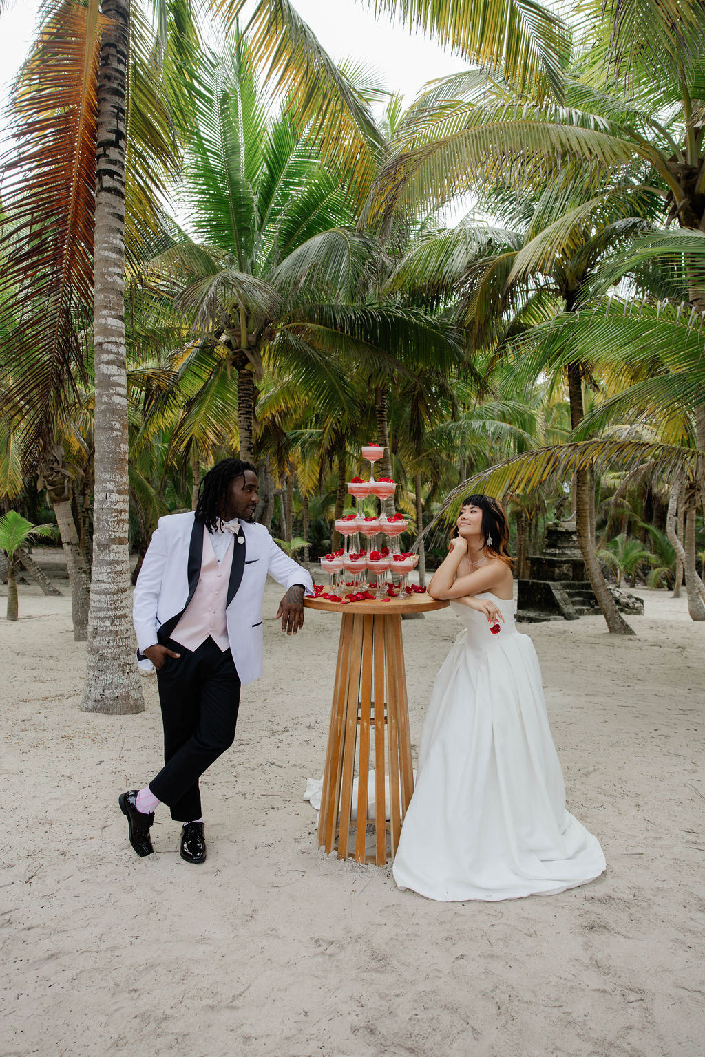 bride and groom pose for a photo with their champagne tower