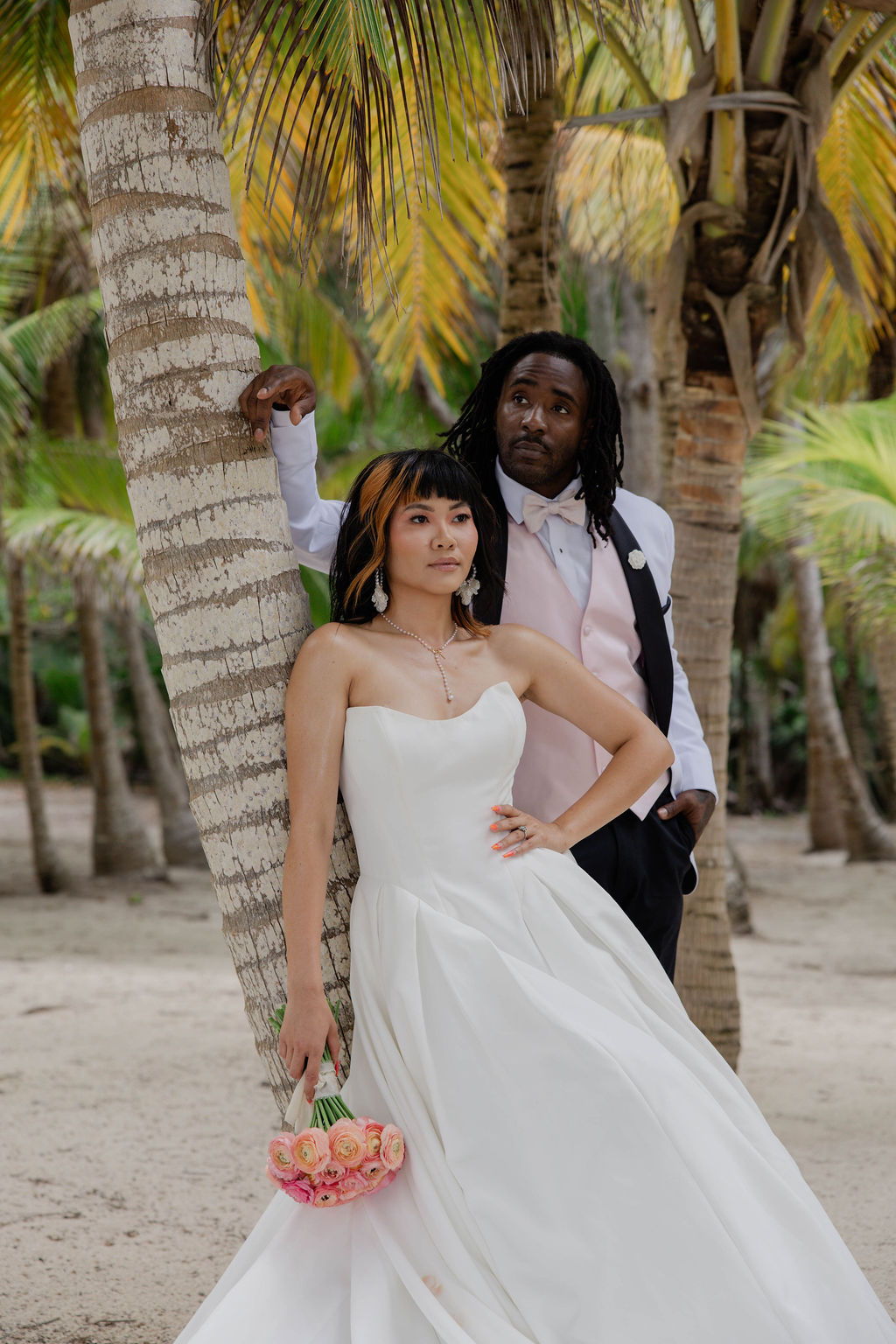 bride and groom poses against a tree during the portraits at riviera maya wedding venue beach