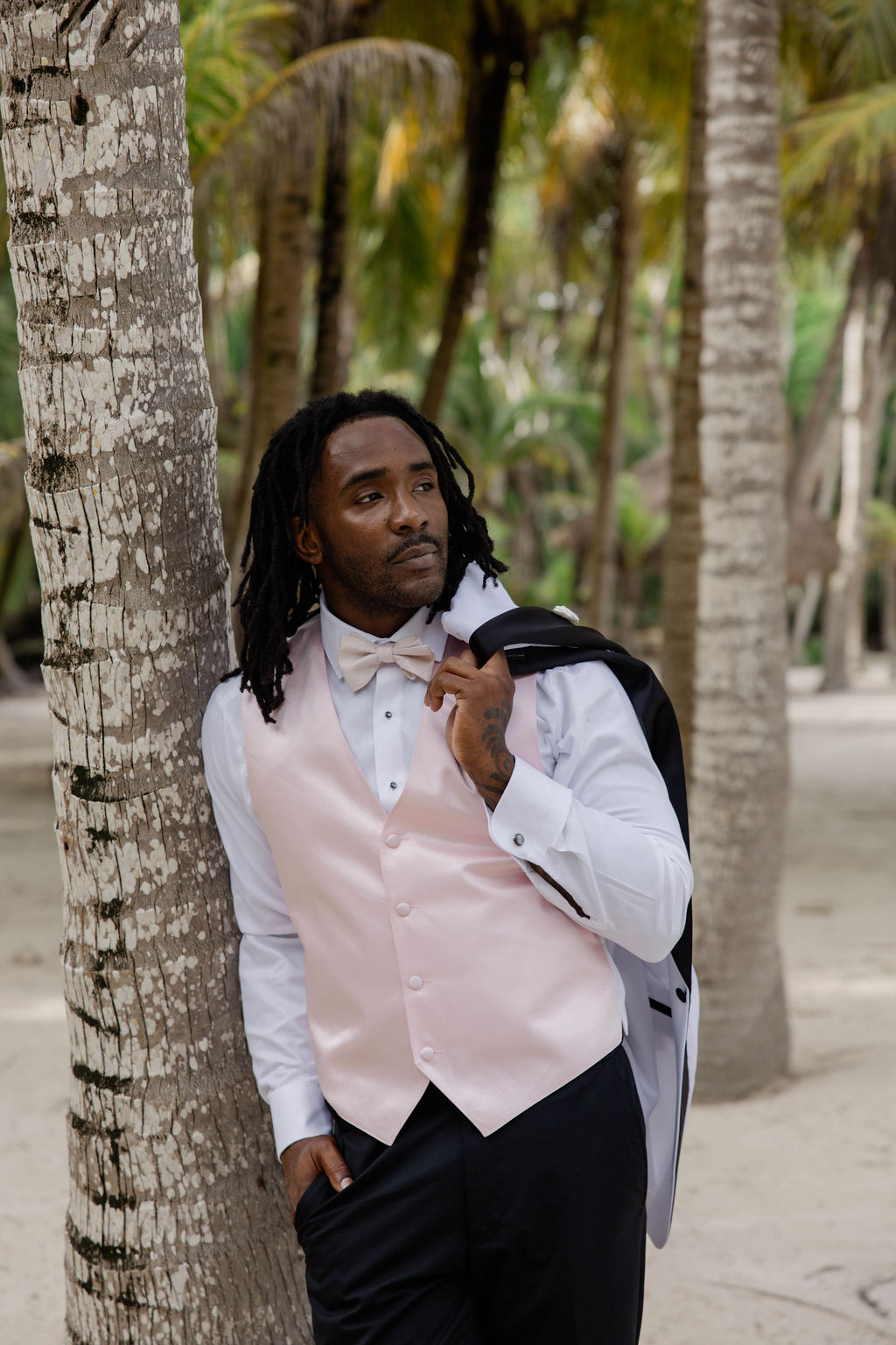 groom poses against a tree during the portraits at riviera maya wedding venue beach