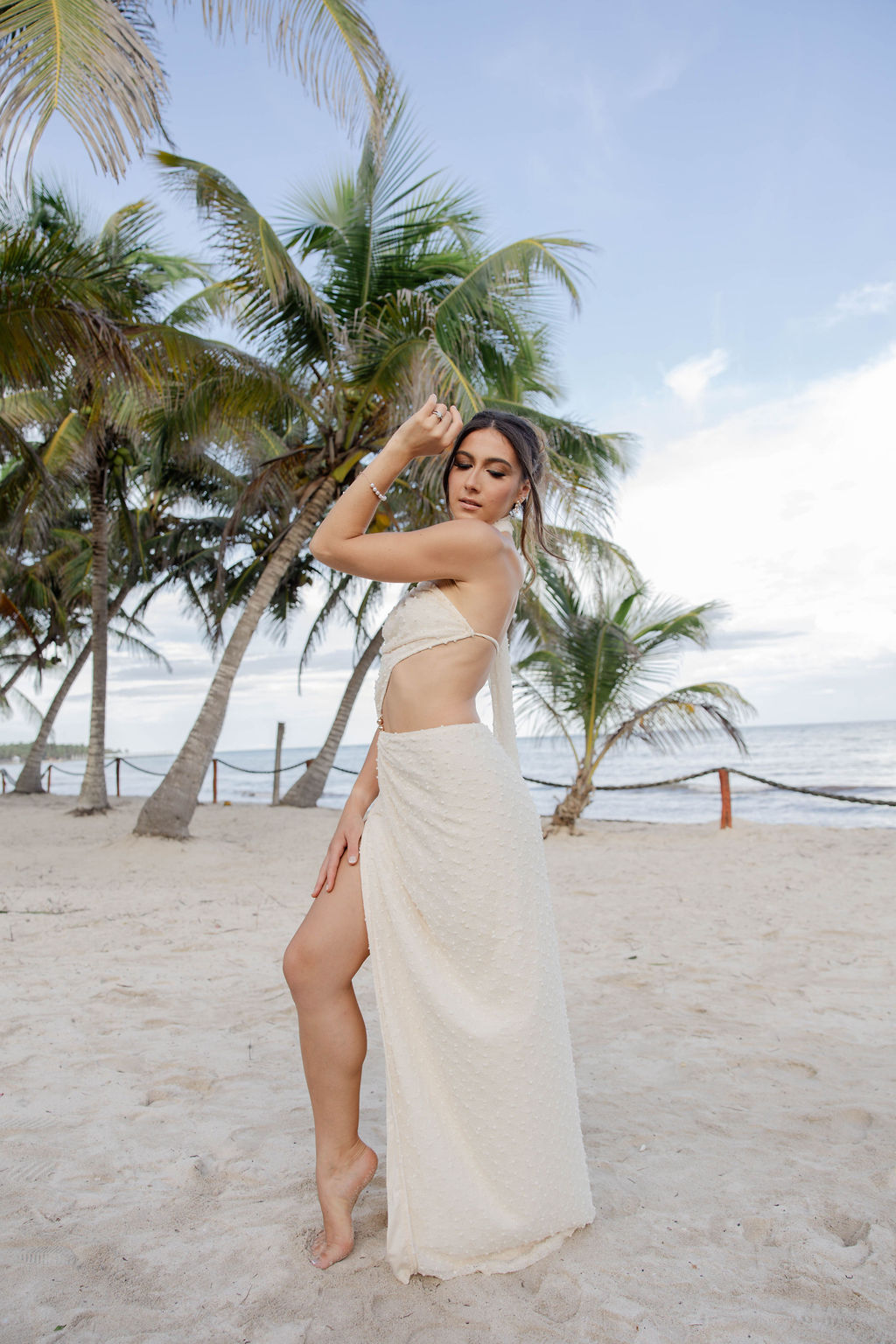 bride poses for a photo on the beach surrounded by the lush tropical vibes