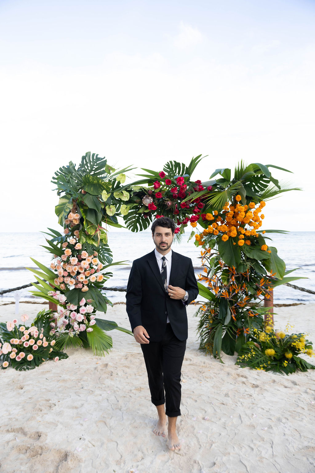 groom walks towards the camera on the private beach