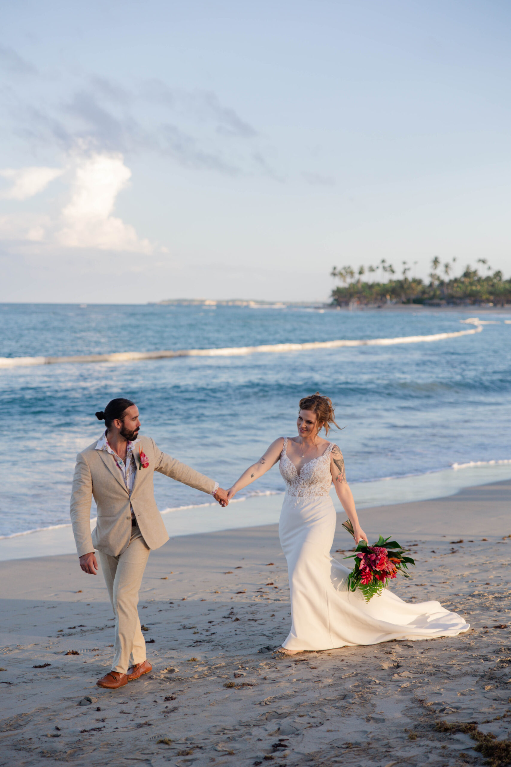 bride and groom walk on the beach together as they celebrate their destination wedding
