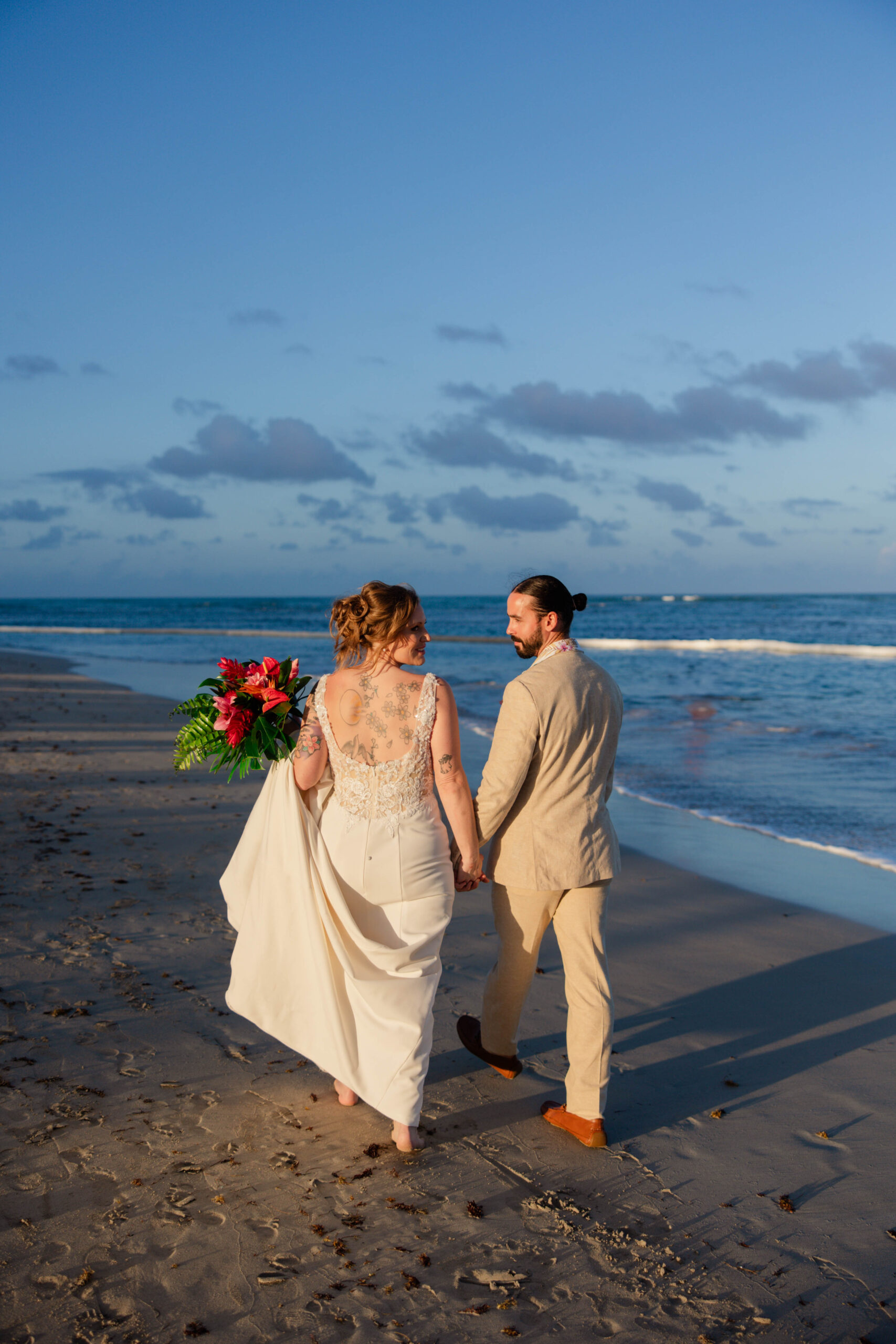 bride and groom walk on the beach together as they celebrate their destination wedding
