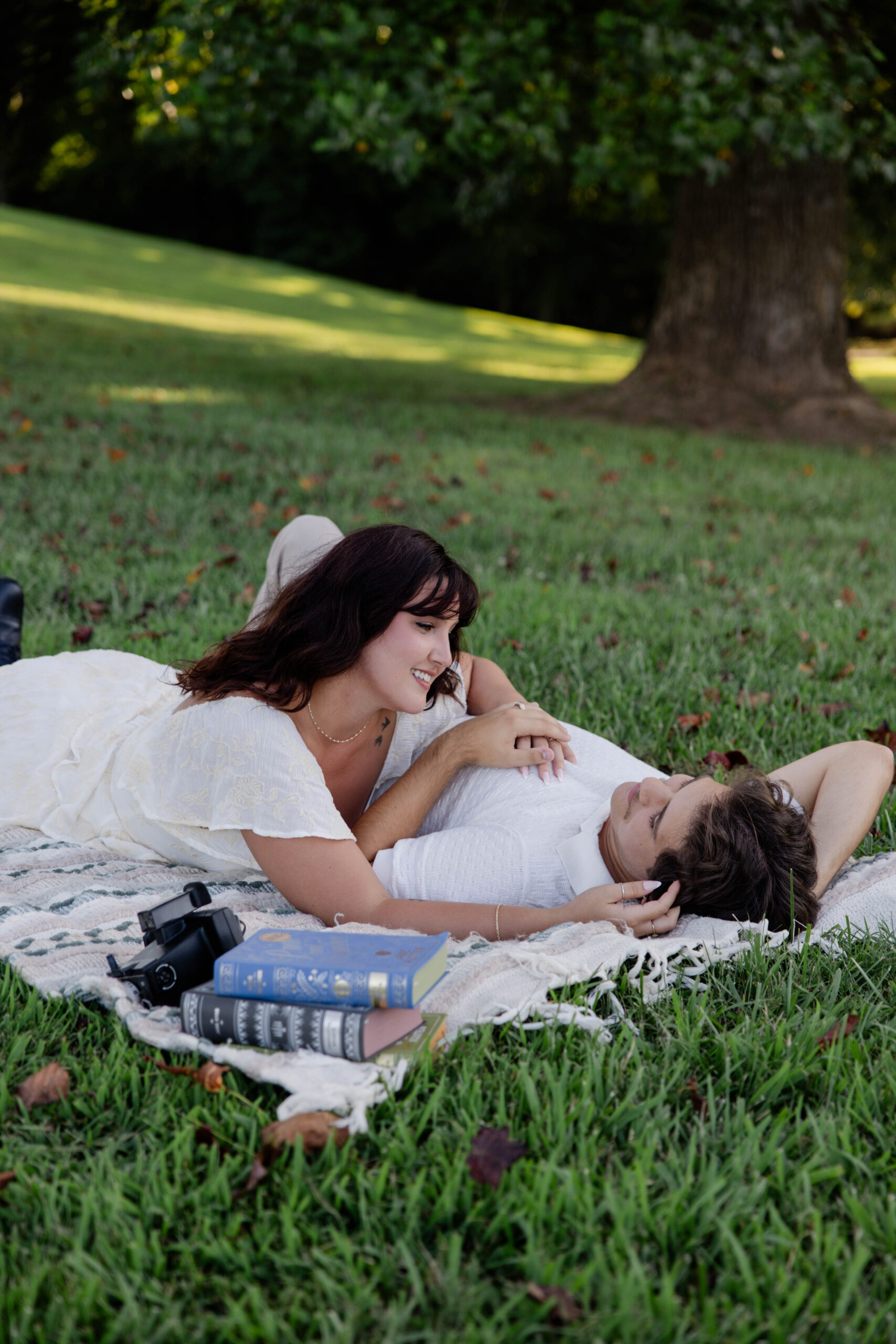 couple lay on a picnic blanket together during their spring engagement photoshoot in Georgia