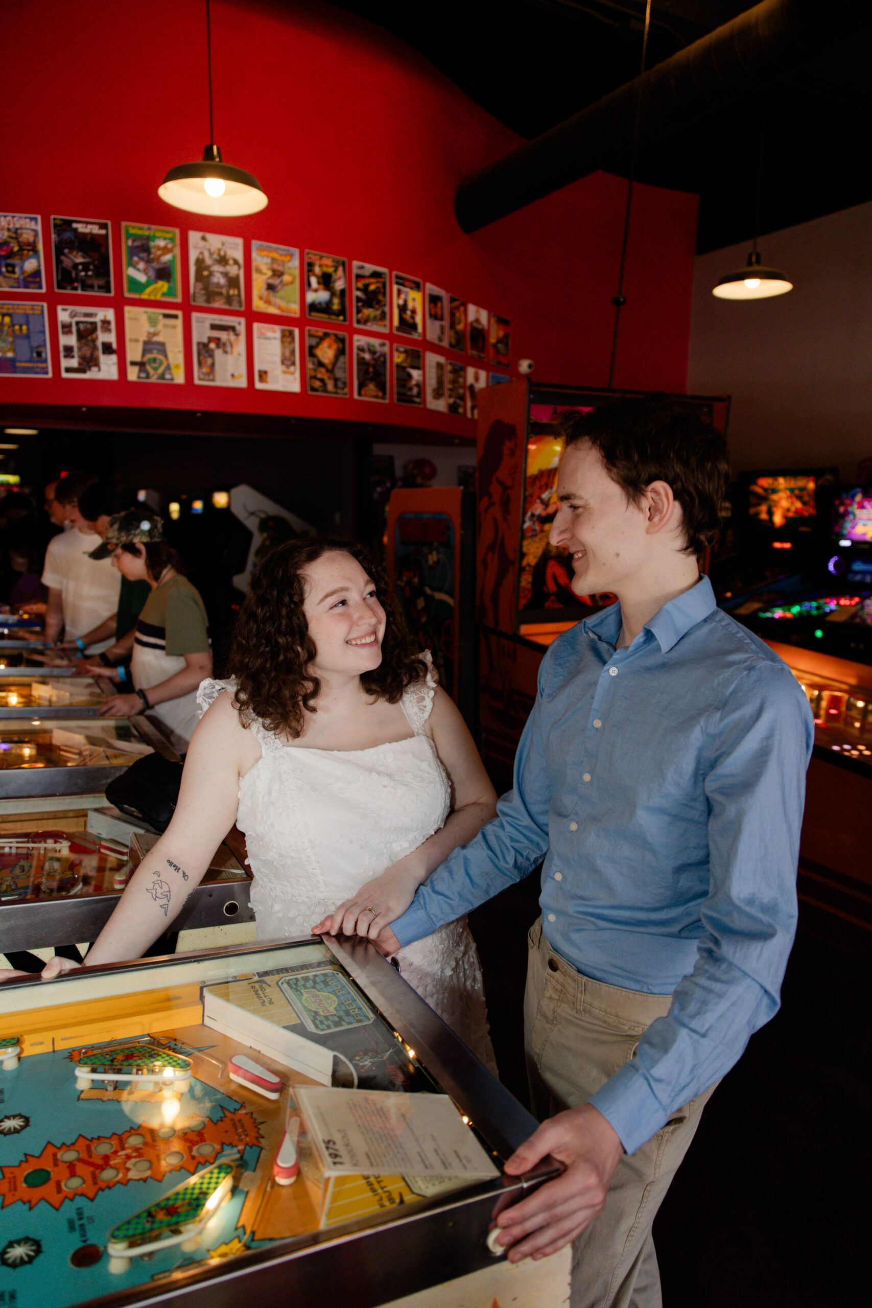 couple hold hands and play pinball together a unique engagement photoshoot idea