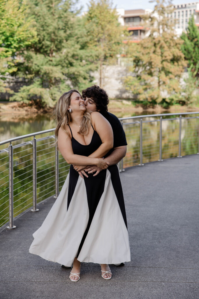 couple laugh and share a kiss during their lakeside engagement session