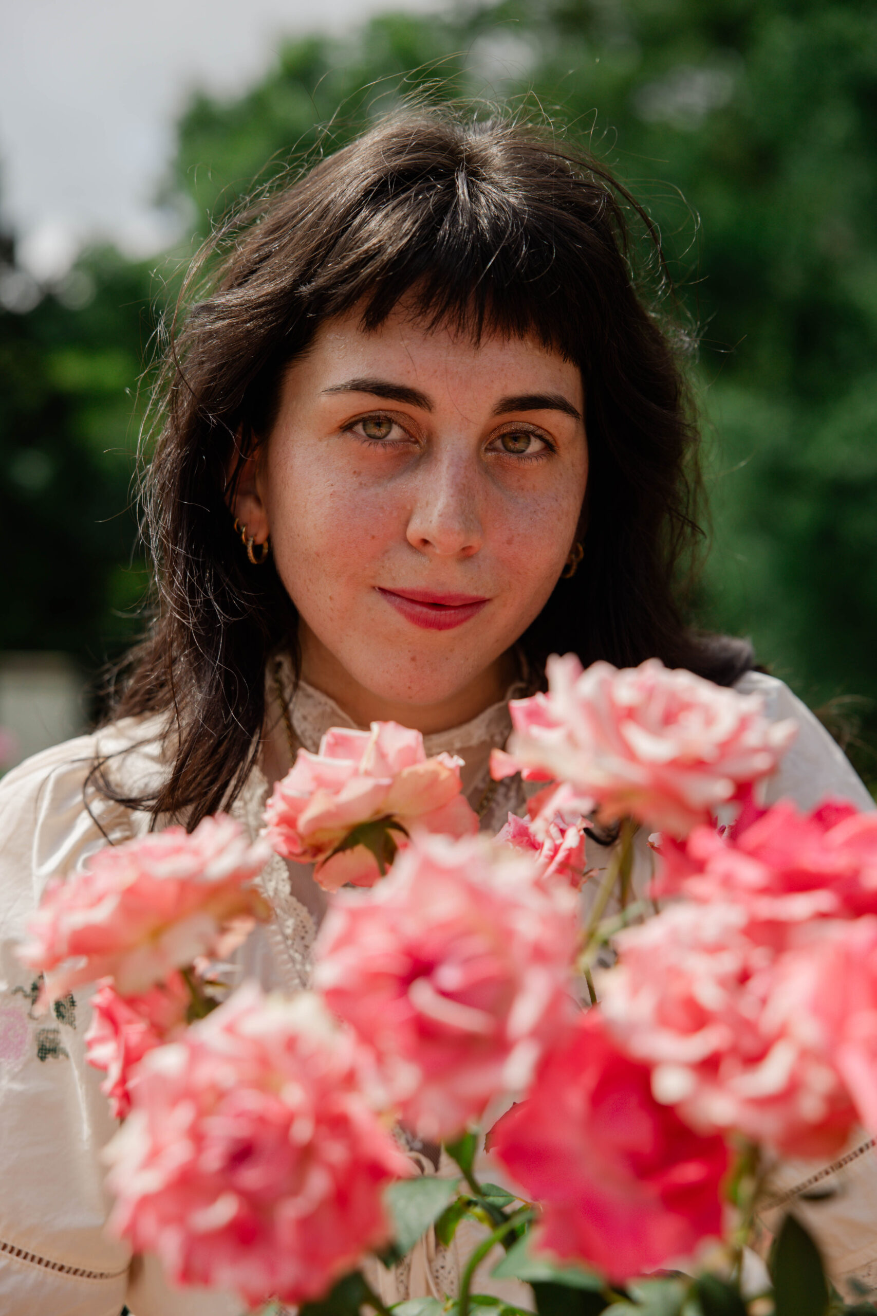 future bride gives a soft smile over her bouquet of pink flowers