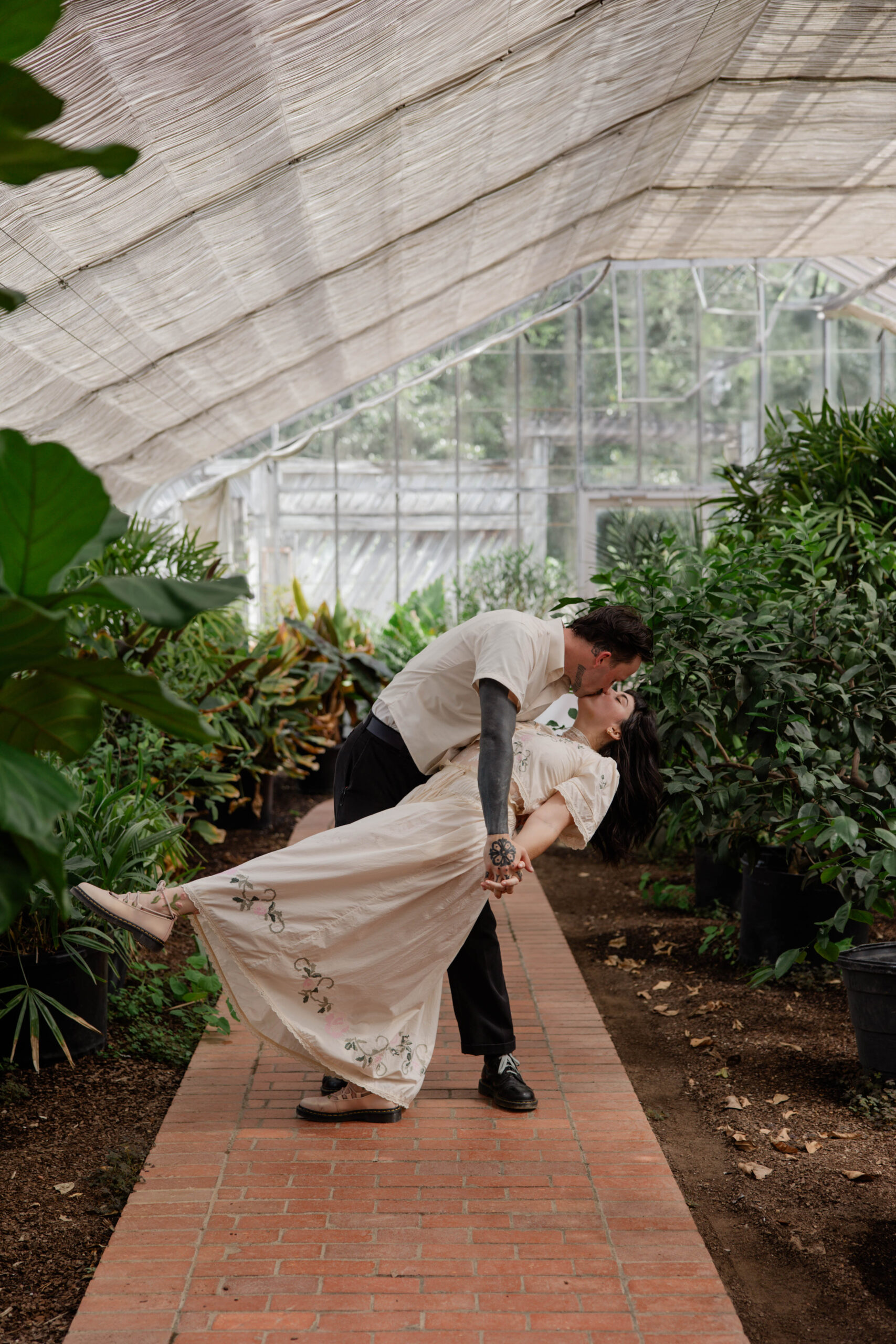 couple share a kiss in the botanical gardens, a kiss is always the a natural engagement photo pose!