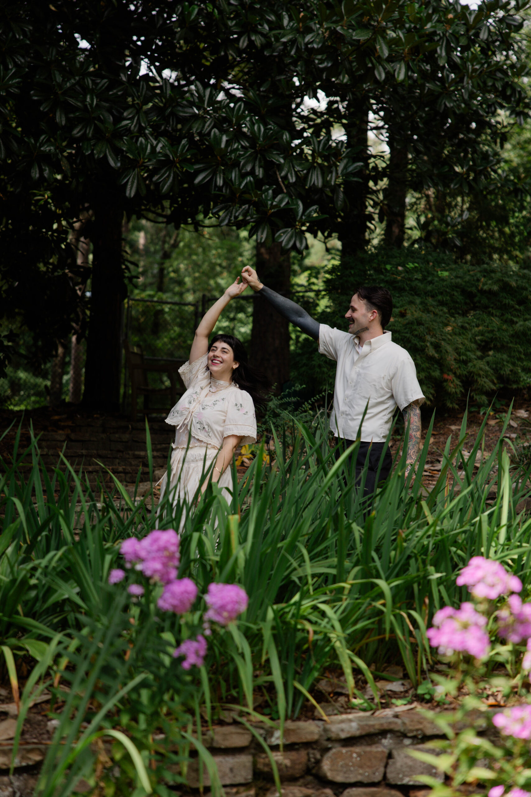 couple dance and laugh together with the purple spring flowers in front of them