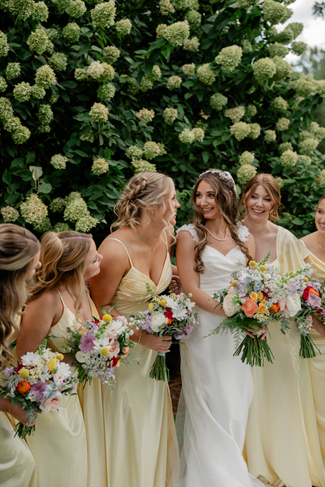 bride laughs and smiles with her bridesmaids during her colorful wedding day