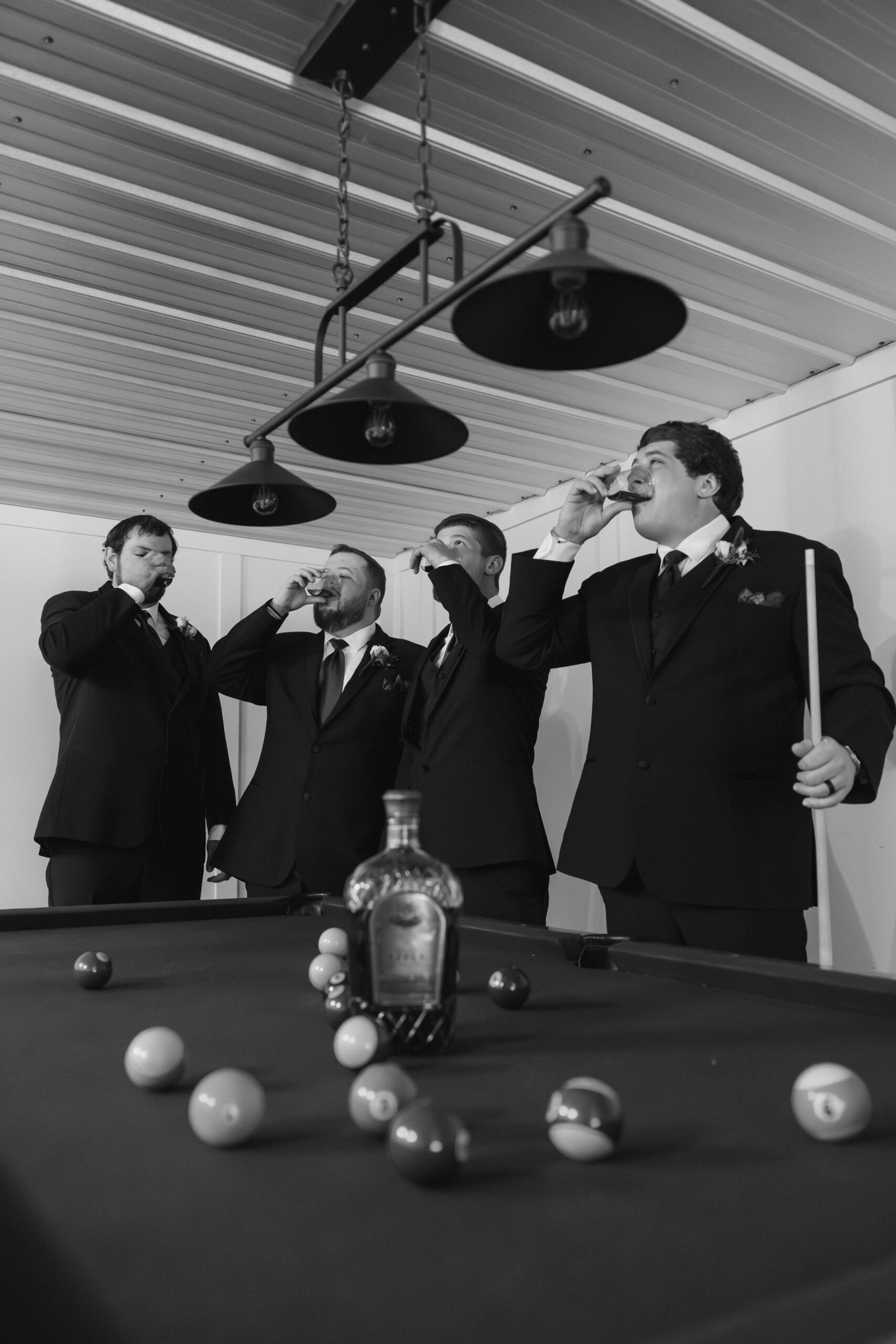 groomsmen celebrate with whiskey and a game of pool as they prepare for the stunning wedding day
