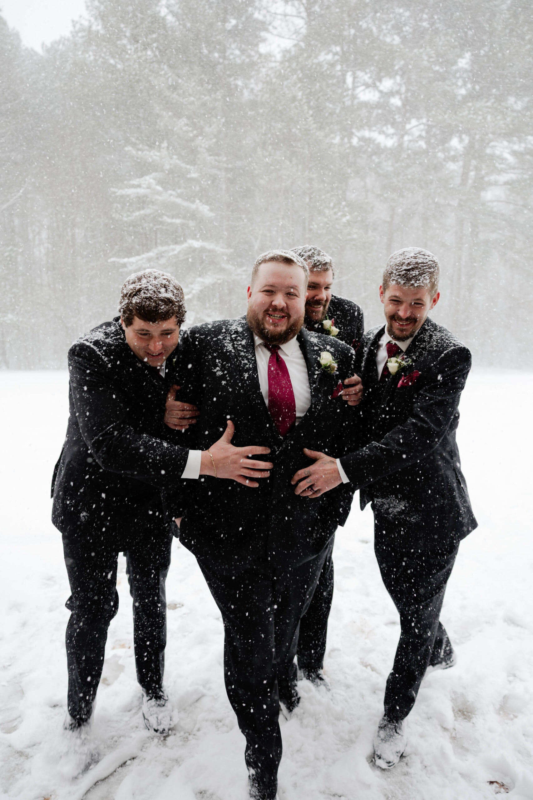 groomsmen celebrate with the groom in the pouring snow