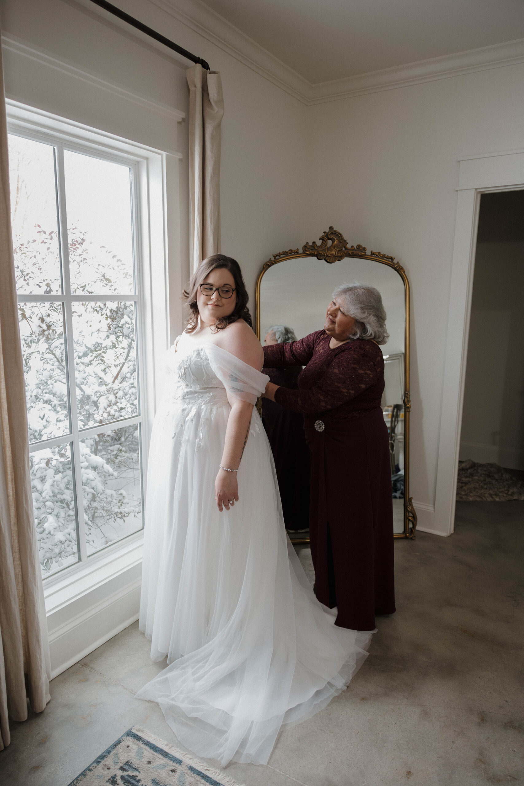 beautiful bride gets help finishing lacing up her stunning wedding dress