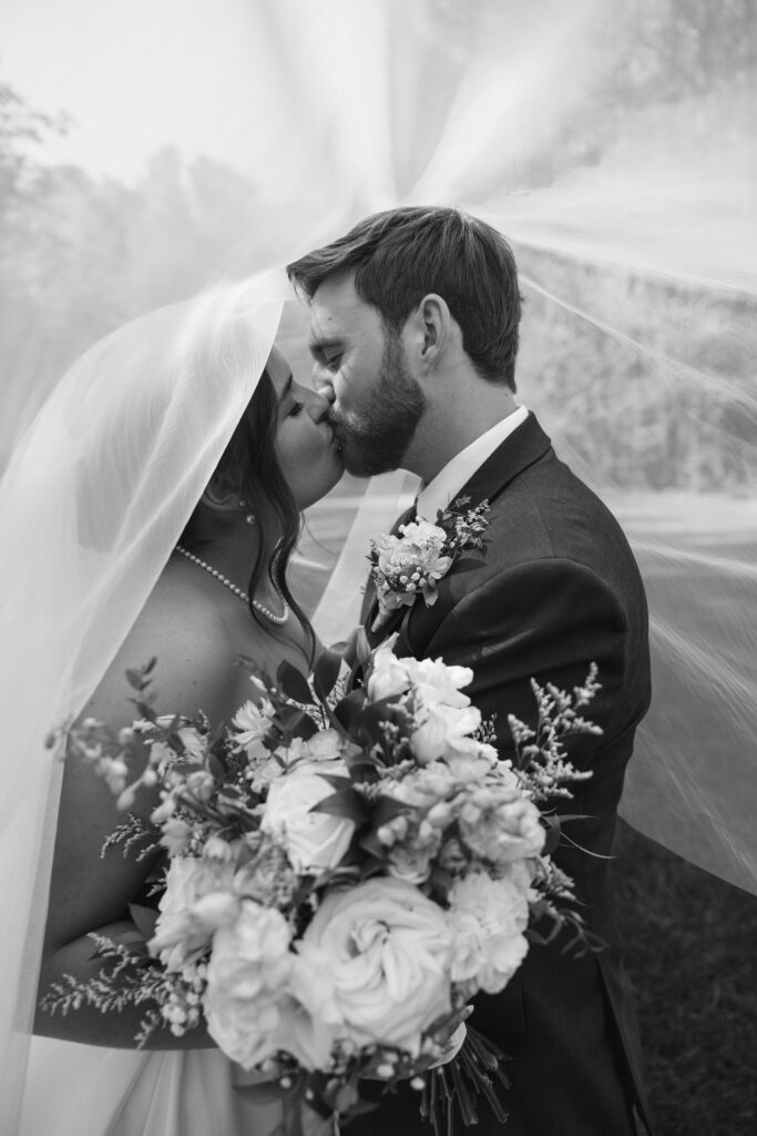 bride and groom share an intimate moment under her veil during their wedding at the butterfly pavilion