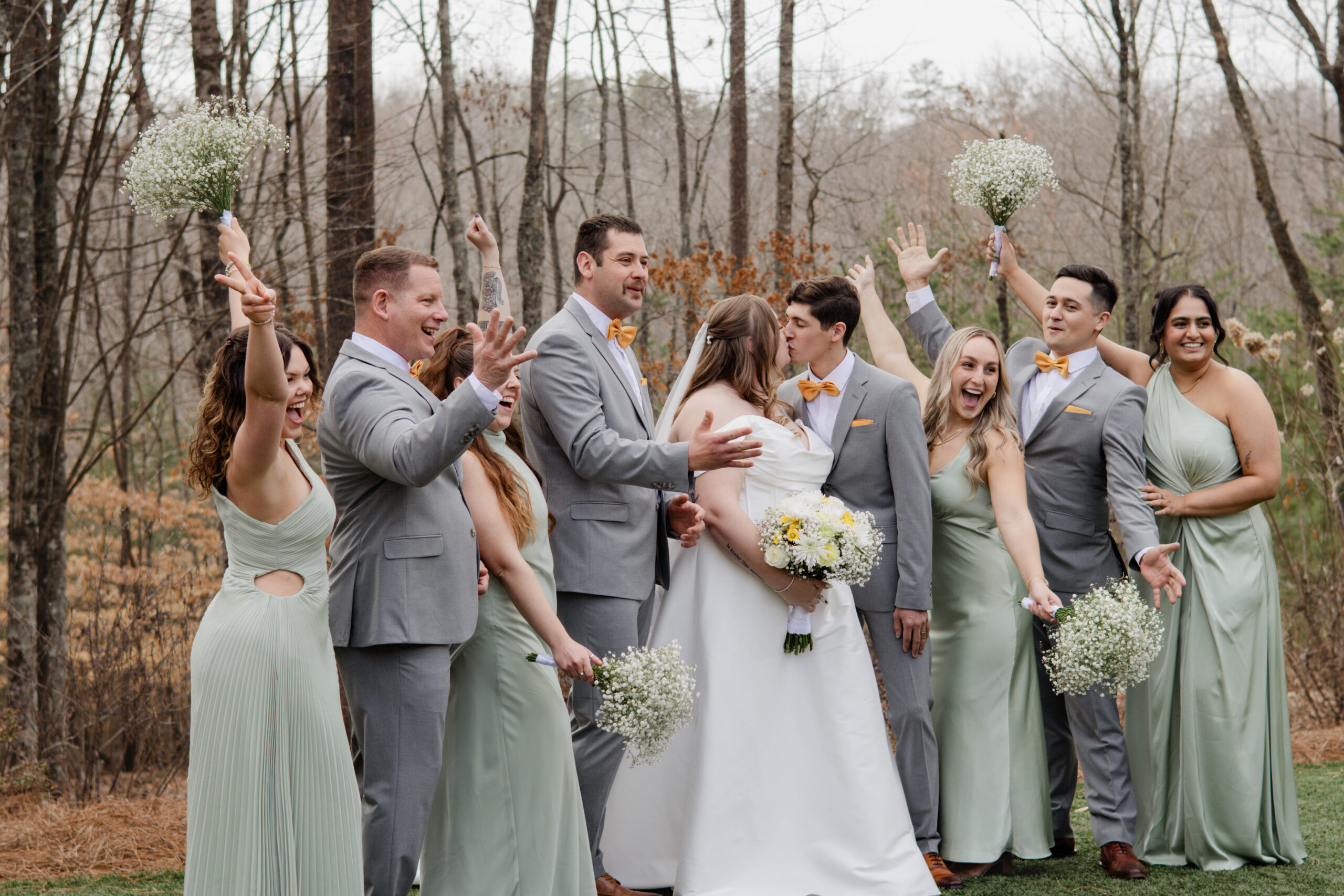 wedding party celebrates as bride and groom share a kiss 