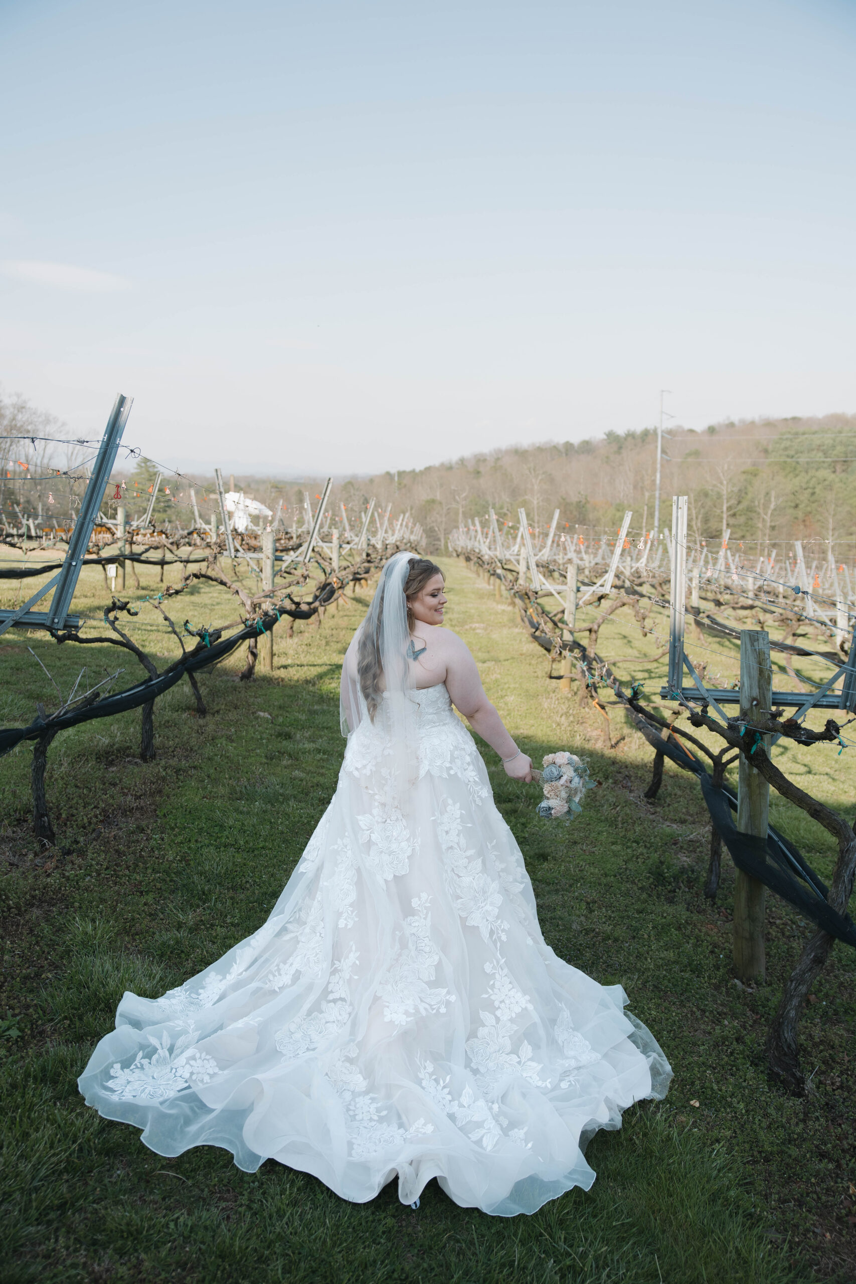 beautiful bride poses for a photo walking through the venue in the vines wedding venue