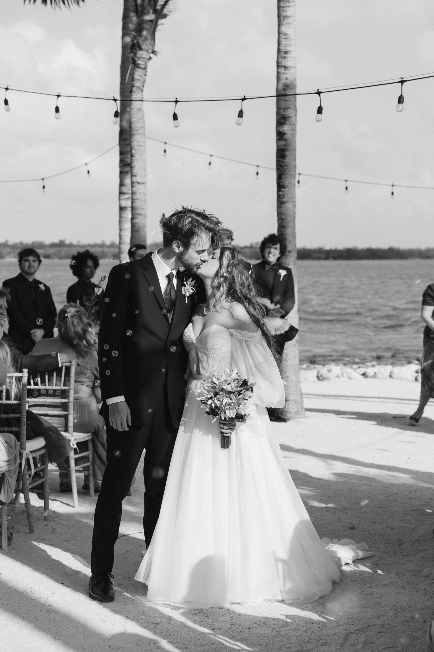 bride and groom share a kiss as they exit their wedding at isla bella