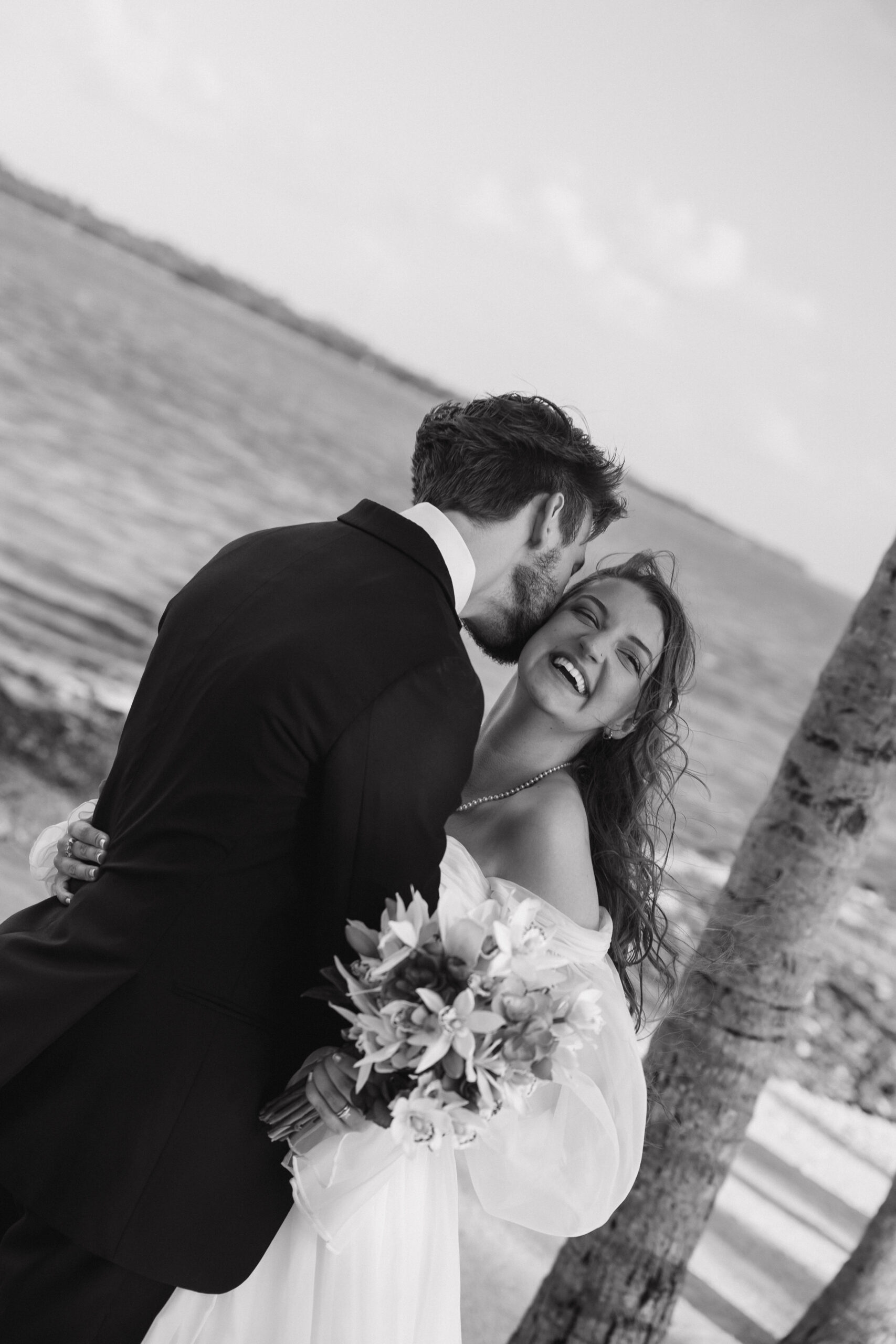 bride and groom share an intimate moment in front of the water