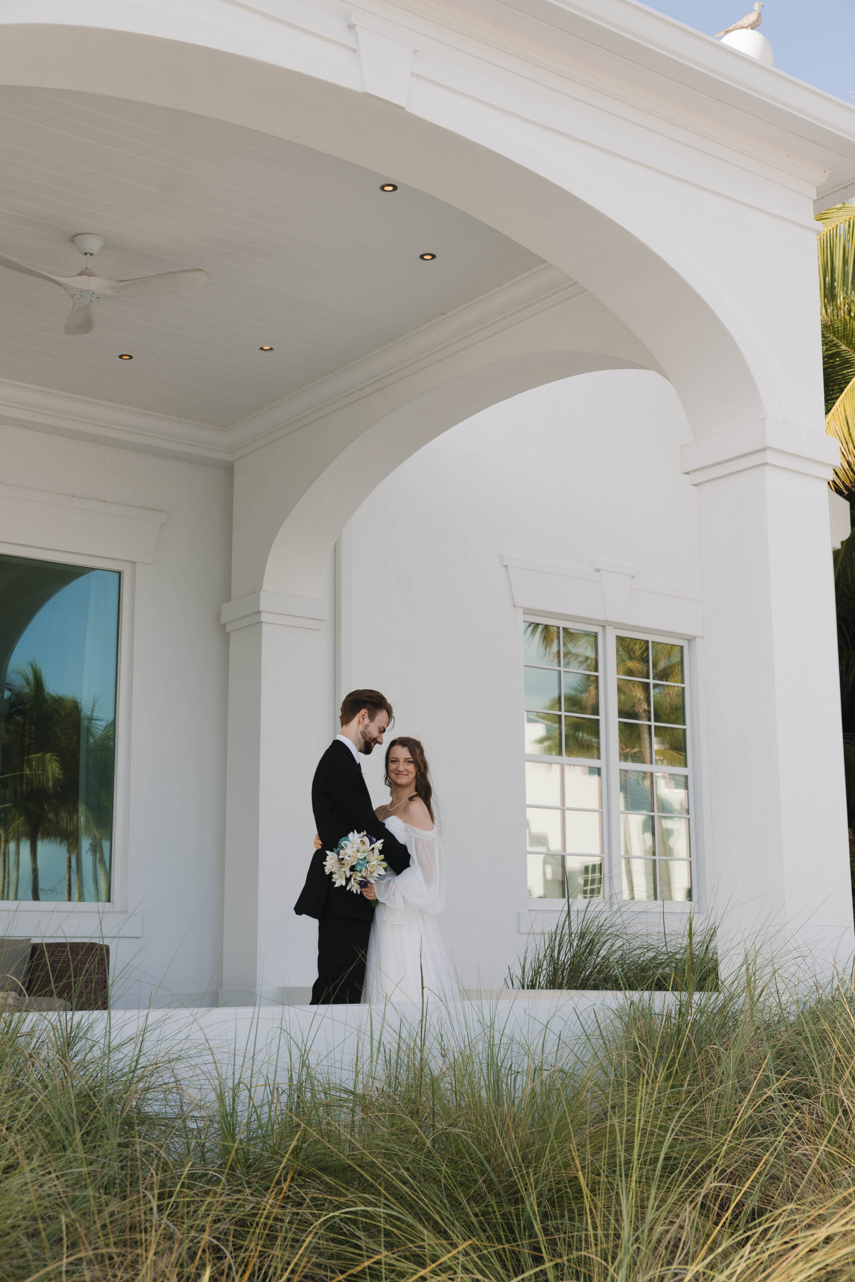bride and groom pose for a photo in front of the stunning venue Isla Bella