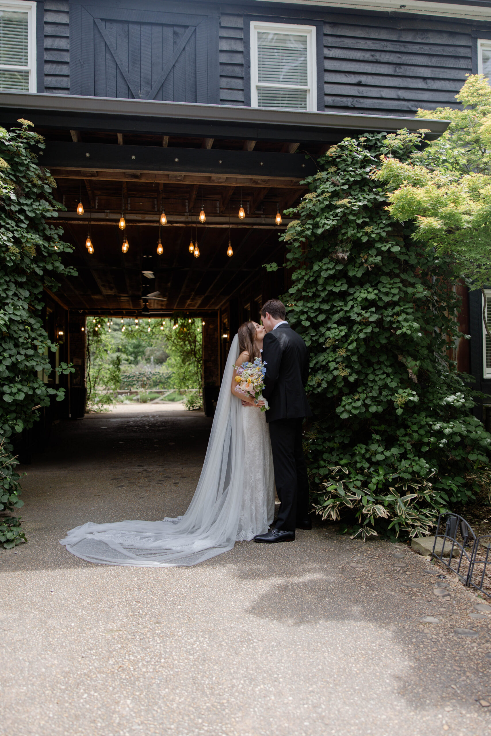 bride and groom share a kiss at the edge of the walkway of the stunning shiloh gardens wedding venue