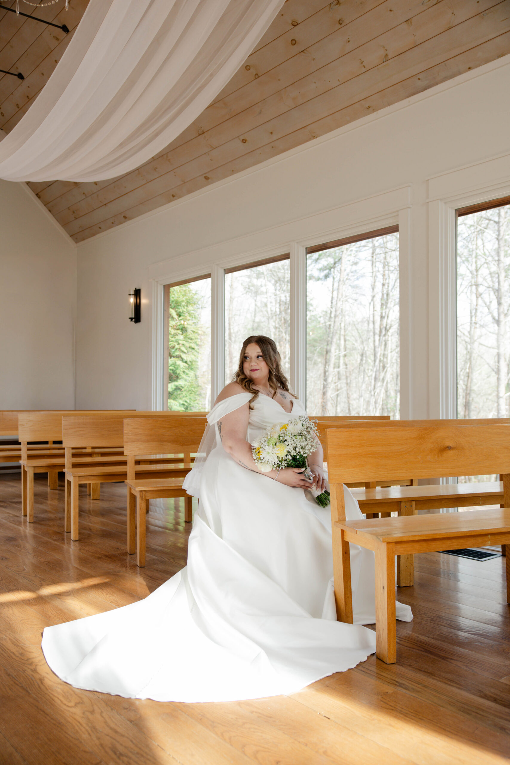 beautiful bride poses for a photo sitting on the bench inside of the stunning juliette chapel