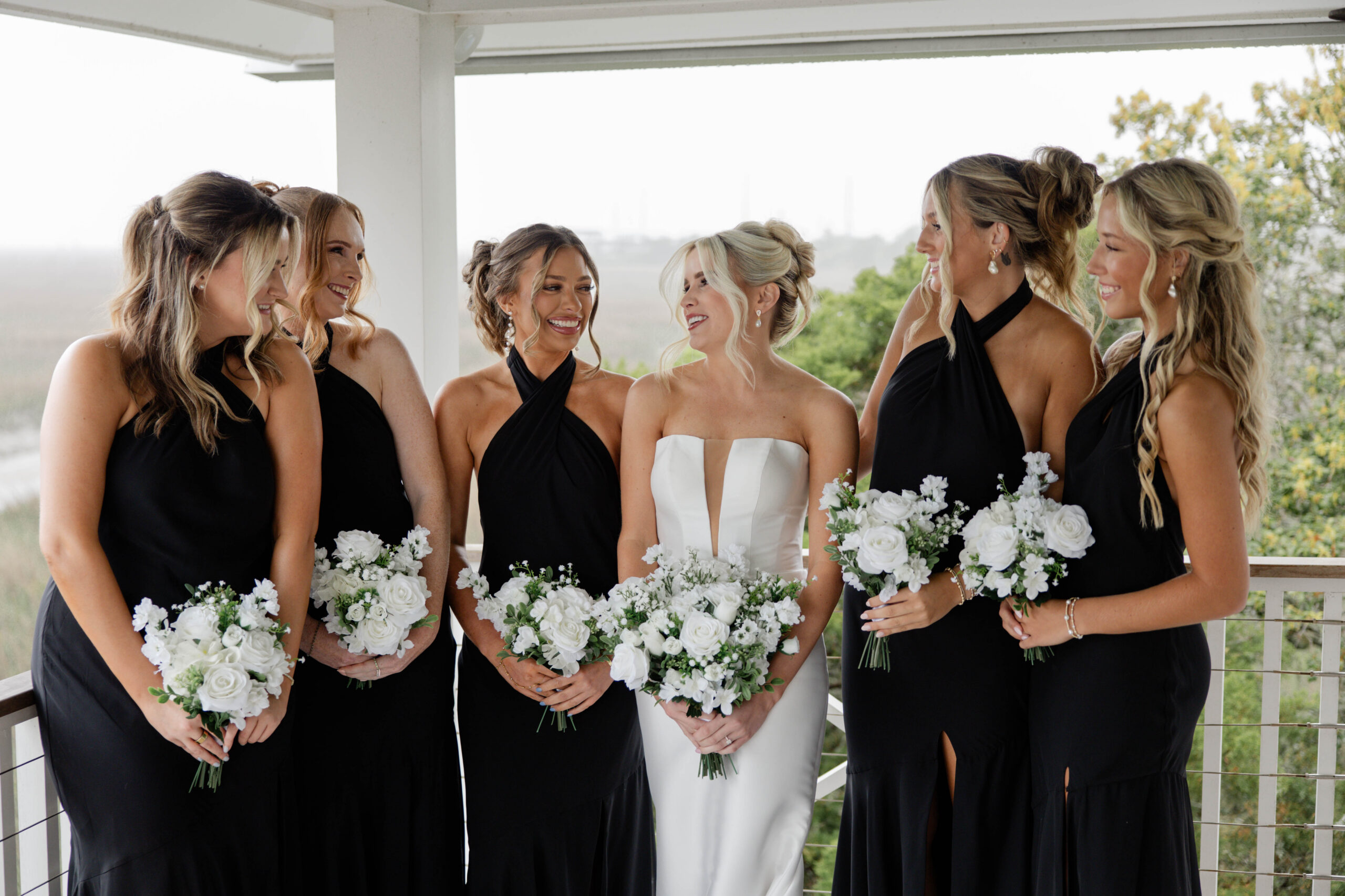 bridal party poses for a photo together with their bouquets
