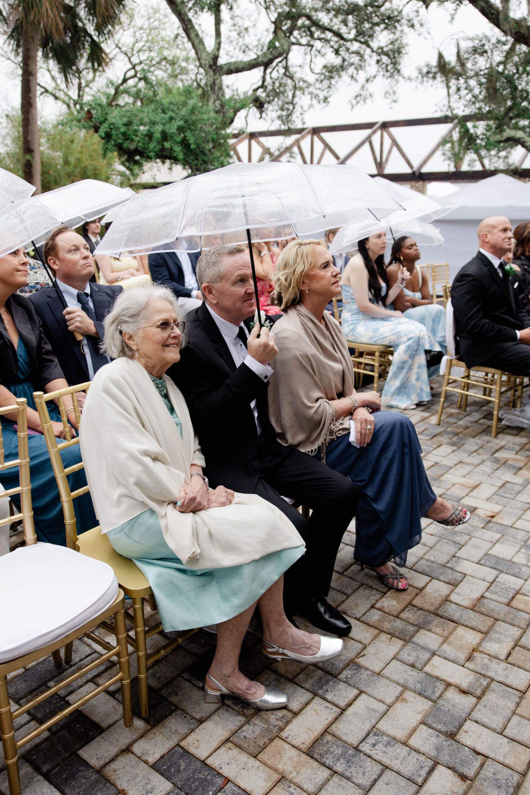 guests sit under clear umbrellas during the stunning spring wedding ceremony