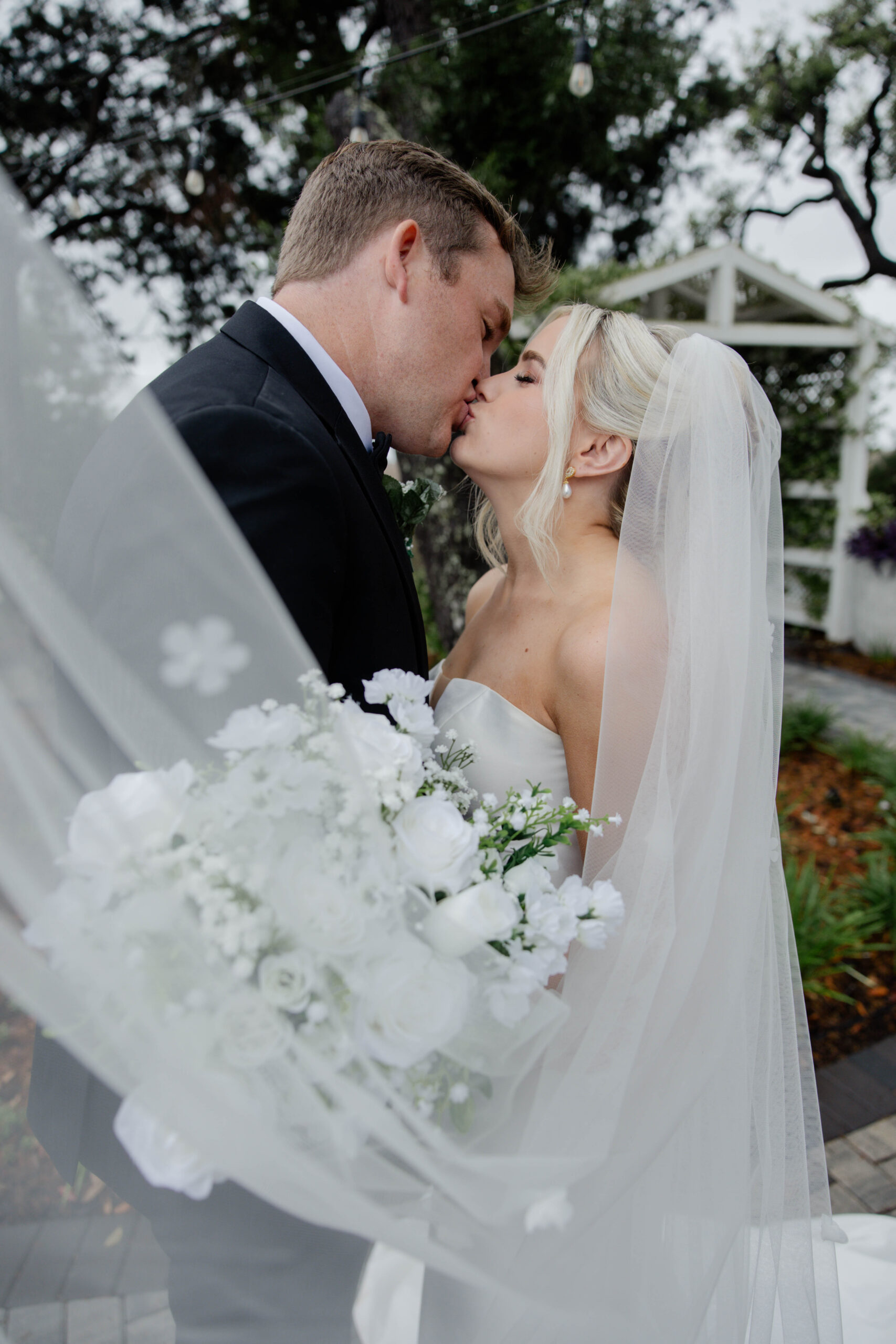 bride and groom share a kiss as the veil wraps around them