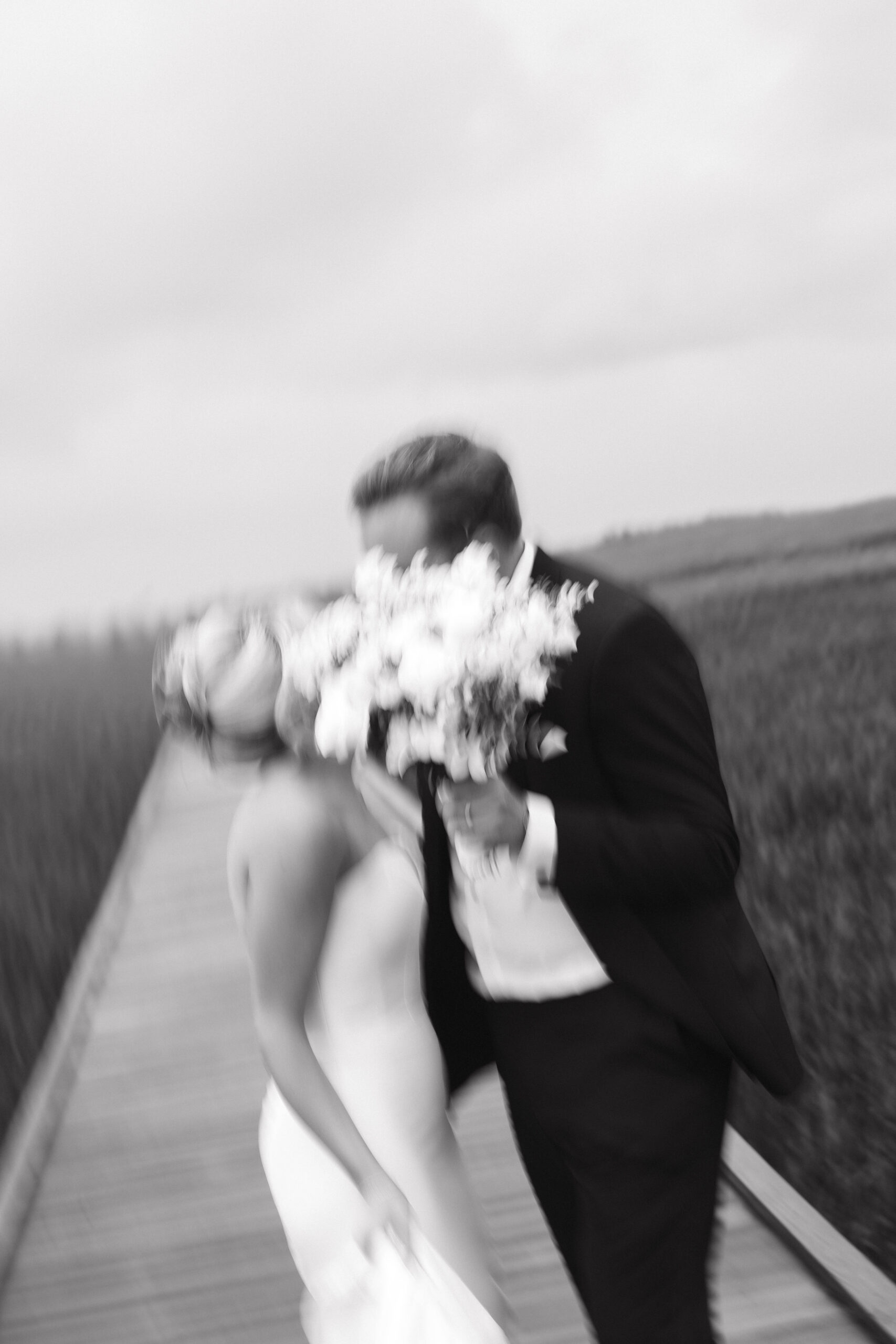 bride and groom joke and dance together on the marshland walking path after their Tybee Island wedding day