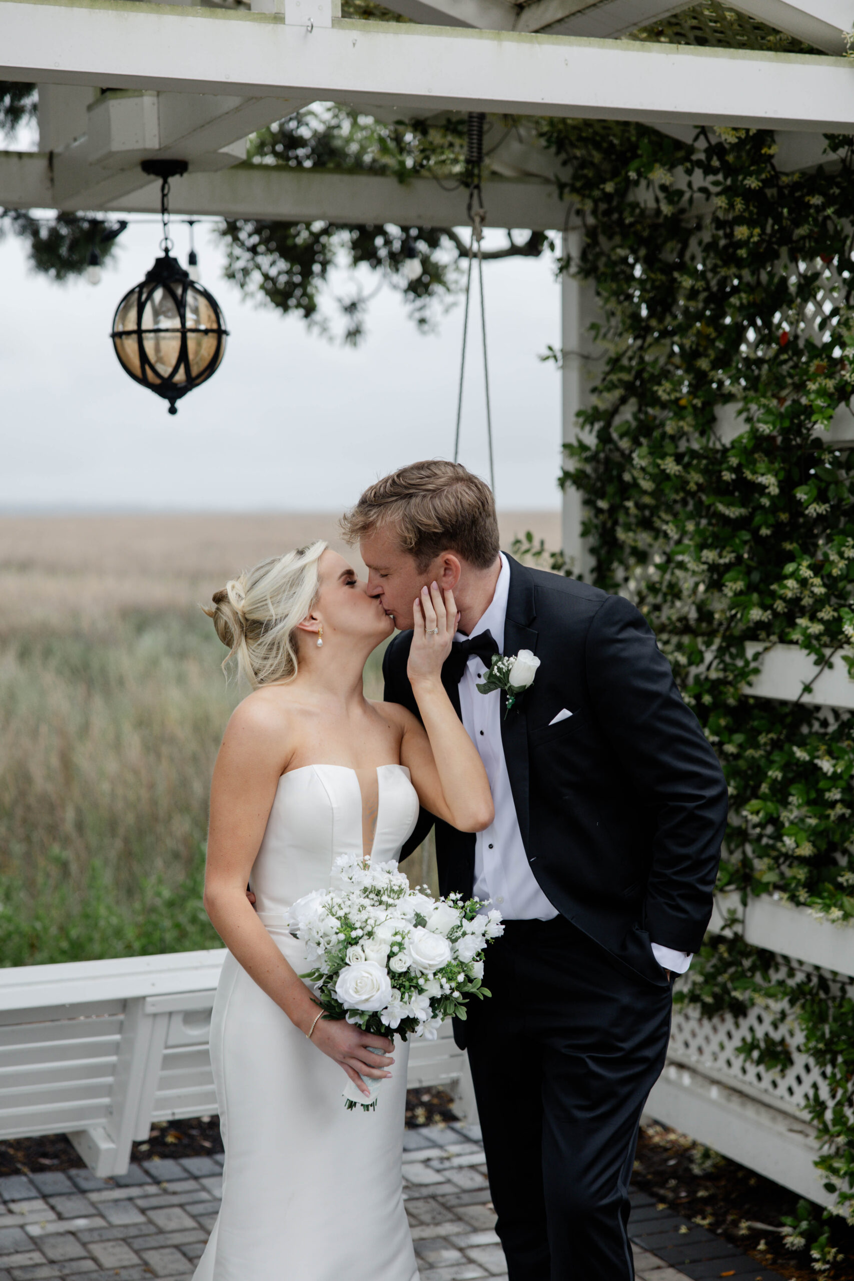 beautiful bride and groom share a kiss at the edge of the marsh